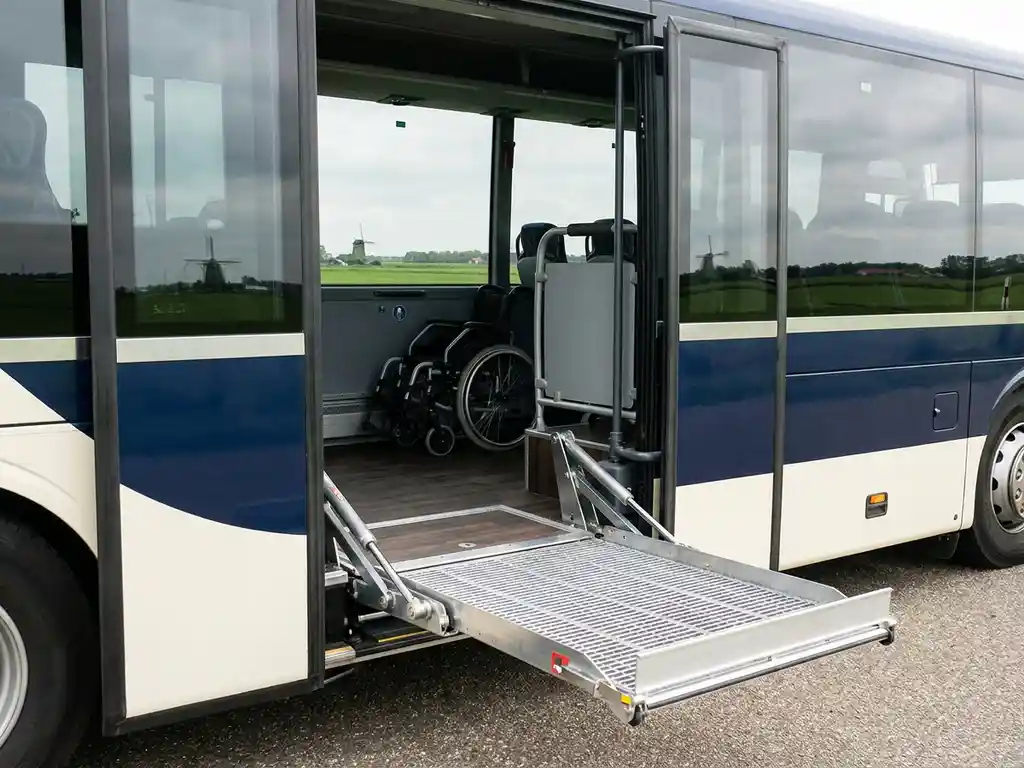 Rolstoellift uitgeschoven bij de instap van een moderne touringcar, met ruim en toegankelijk interieur.